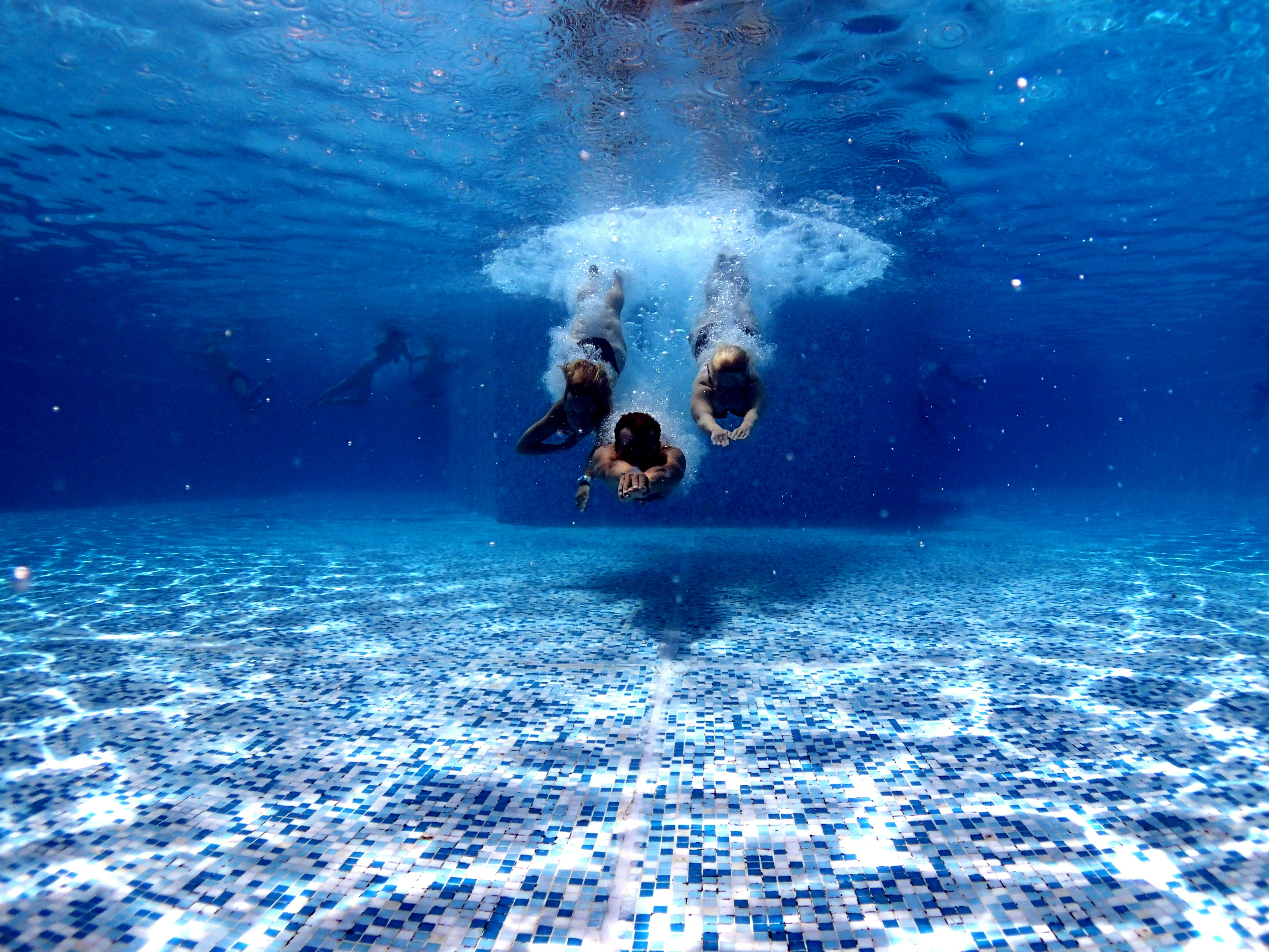 Three Person Diving Into the Pool